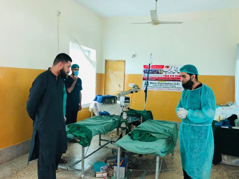 An operating theatre with green-draped beds and medical staff in scrubs.