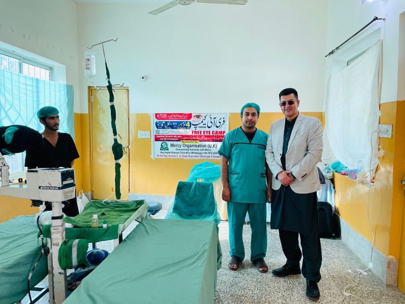 Two men, one in surgical scrubs, standing in a hospital operating theatre.