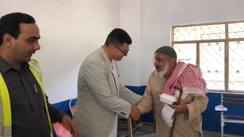 A volunteer handing medicine to a woman at a free eye camp.