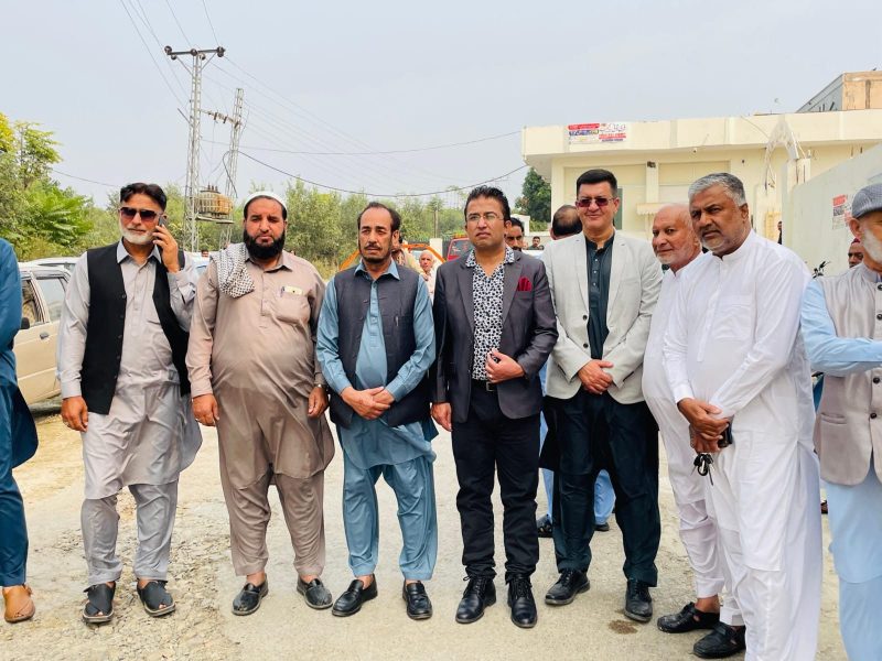A group of men standing together outside a building in the hills.